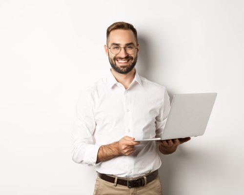 Business. Sucessful businessman working with laptop, using computer and smiling, standing over white background.